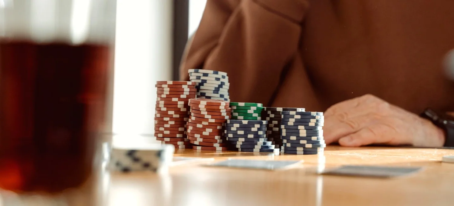 Poker chips and a glass of dark tea on a warm wooden table